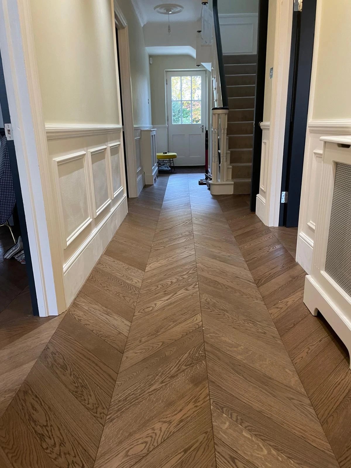Smoked oak chevron floor laid down a panelled hallway