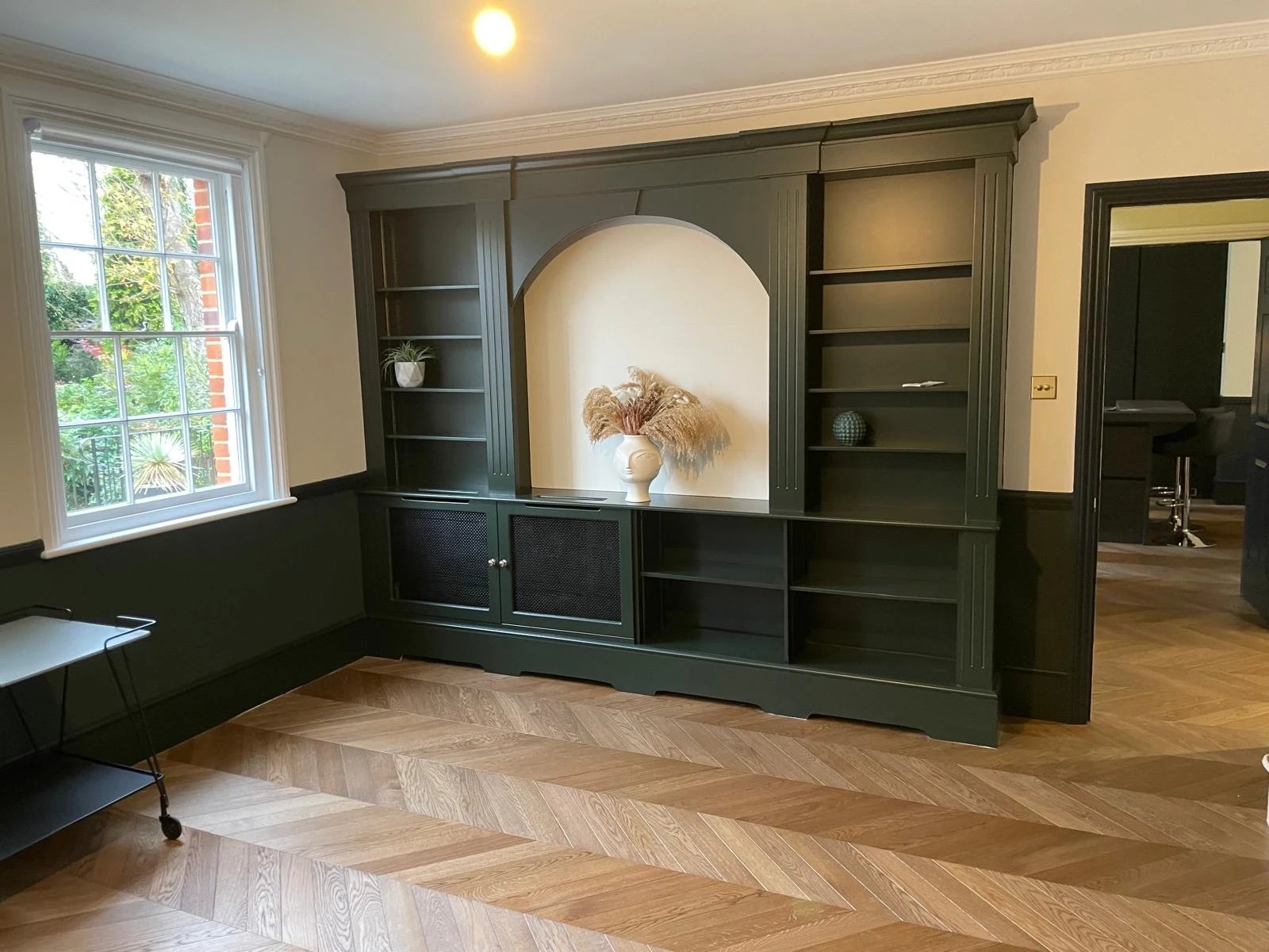Deep green bespoke bookcase wall with an arched niche